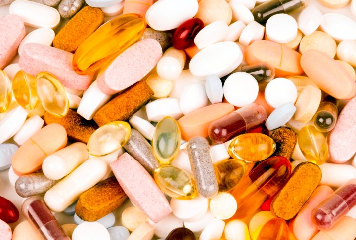 Assorted tablets, capsules and softgels arranged on a white surface.